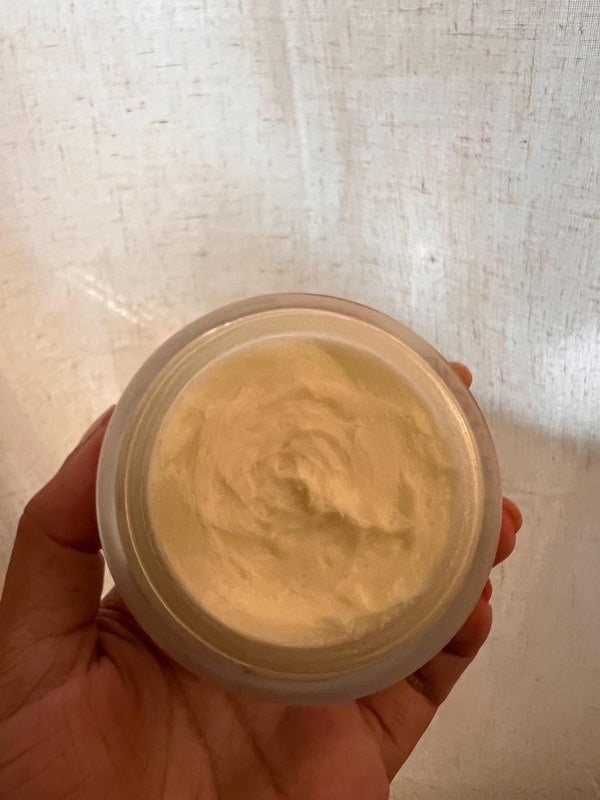 Open jar of whipped Minerva body butter held in a hand