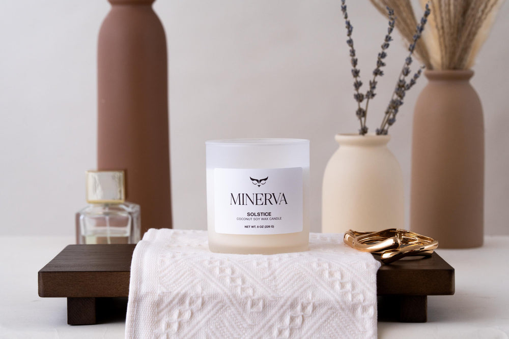 Minerva Solstice coconut soy candle nestled in green moss on a wooden table