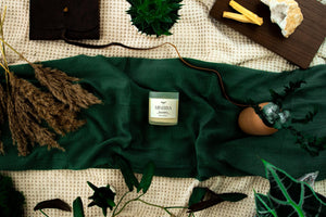 Minerva Palo Santo candle on a deep green linen cloth