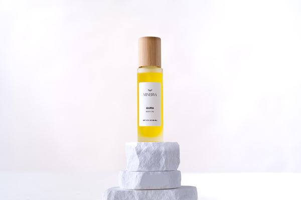 Minerva Aura body oil in a frosted glass bottle with bamboo cap on a white plinth