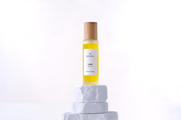 Minerva Luna body oil in a frosted glass bottle on a white plinth