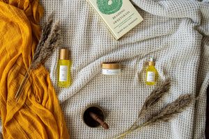 Minerva Sol body oil and Luna body butter on a cream waffle blanket