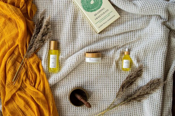 Minerva Sol body oil and Luna body butter on a cream waffle blanket
