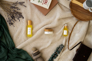 Minerva body oils and body butter styled on a cream blanket with a mustard scarf