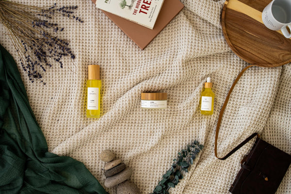 Minerva body oils and body butter styled on a cream blanket with a mustard scarf