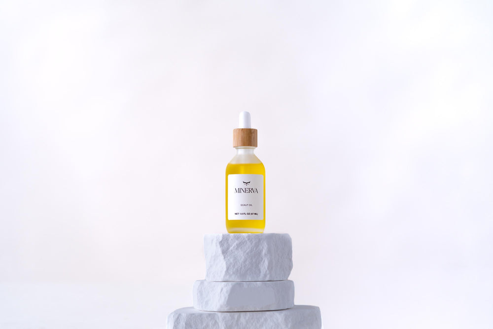 Minerva Scalp Ritual Oil dropper bottle with bamboo cap on a white stone plinth