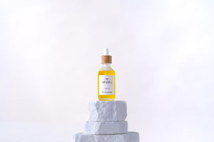 Minerva Scalp Ritual Oil dropper bottle with bamboo cap on a white stone plinth