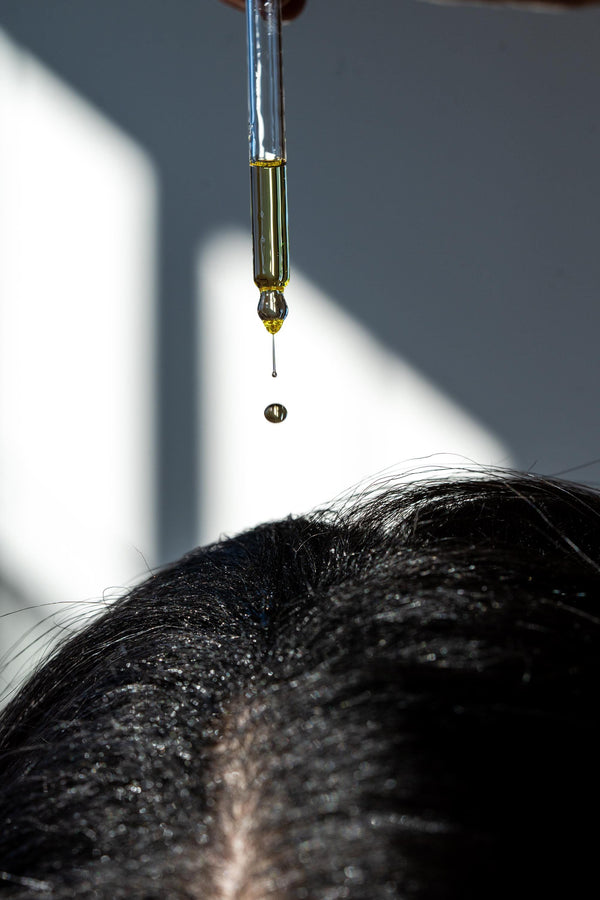 A drop of Minerva Scalp Ritual Oil falling from the dropper onto the scalp
