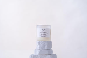Minerva Palo Santo 8 oz frosted glass candle on a white stone plinth