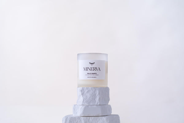 Minerva Palo Santo 8 oz frosted glass candle on a white stone plinth