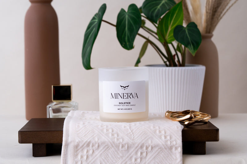 Minerva Solstice candle on a wooden tray with a linen cloth and vase