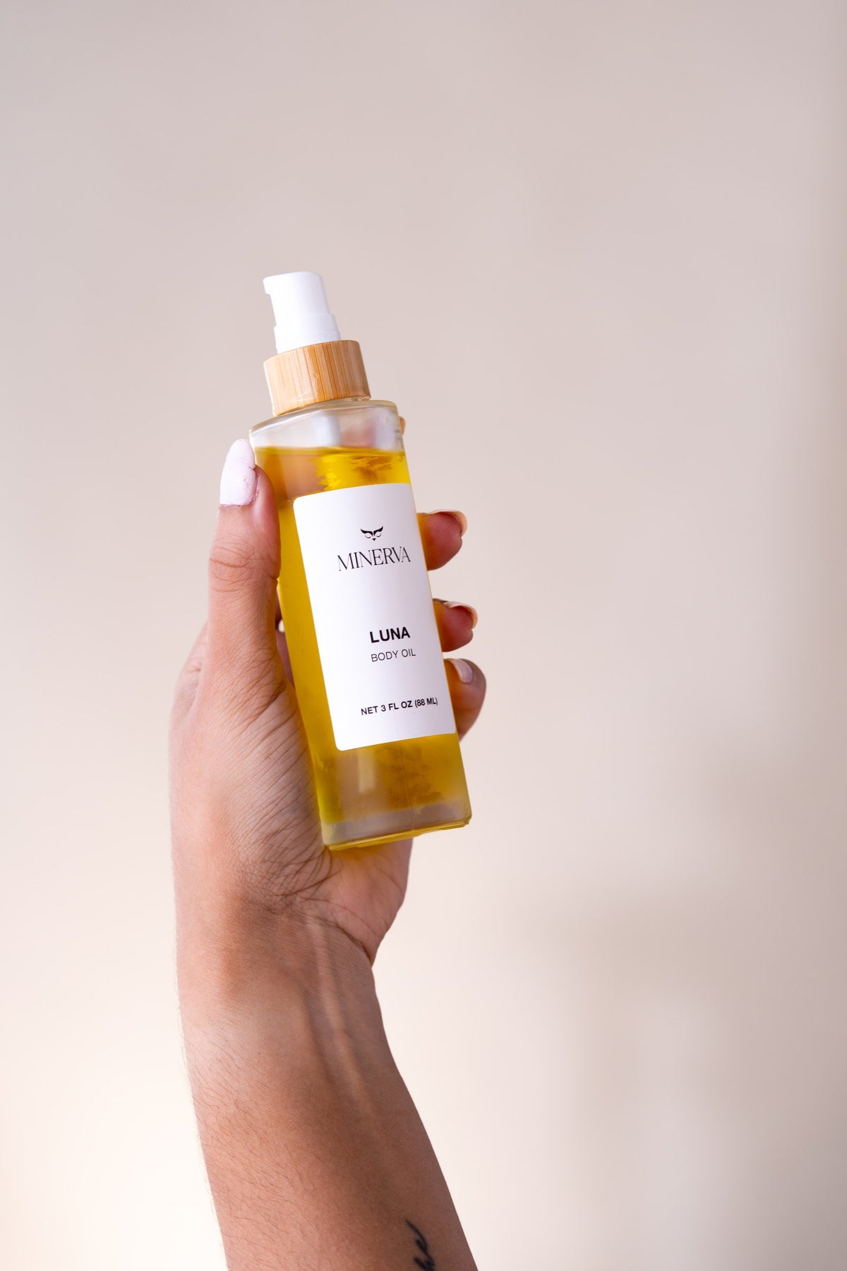 Hand holding a bottle of Minerva Luna body oil