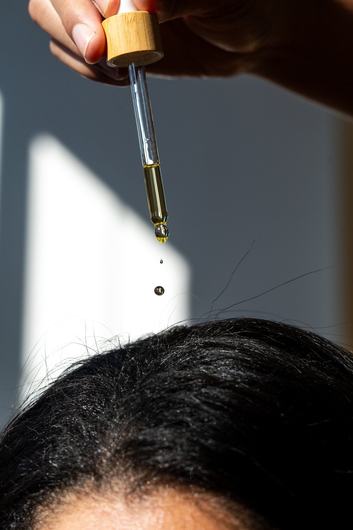 A drop of Minerva Scalp Ritual Oil falling from the dropper onto the scalp