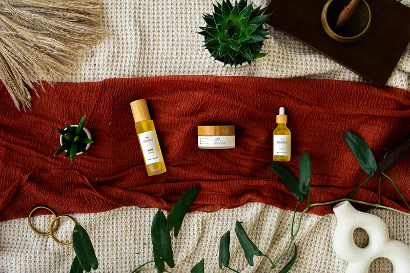 Minerva Aura body oil, body butter and scalp oil on a rust linen cloth