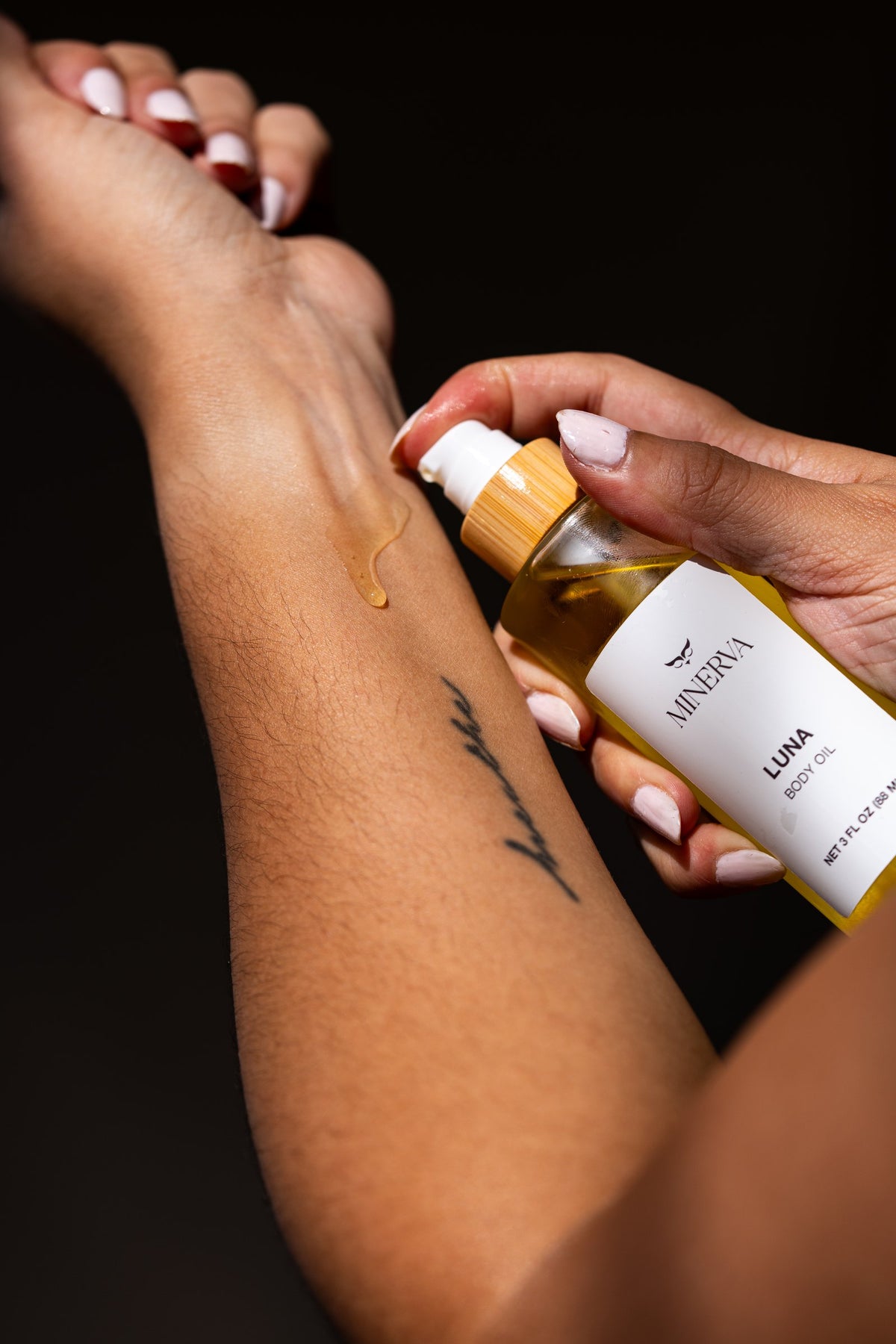 Minerva body oil being applied to the arm in warm light